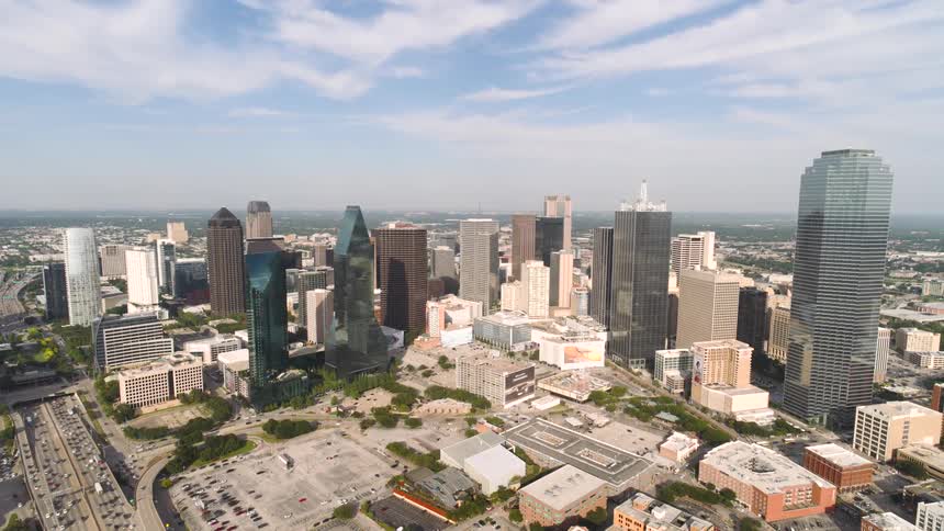 The freeway by the tall buildings is packed with cars