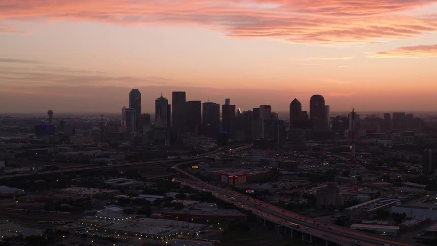 An aerial view of a metropolitan city with the center featuring huge buildings and a day with an orange sky