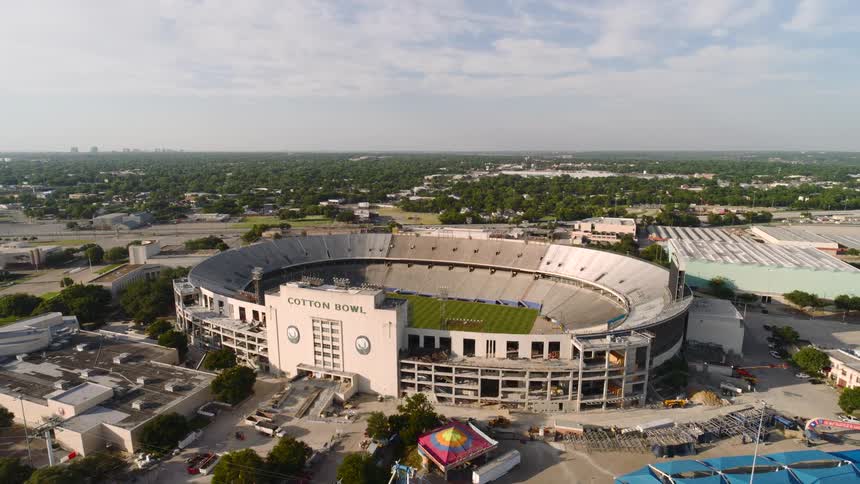 A stadium building with an open roof located in the city at midday