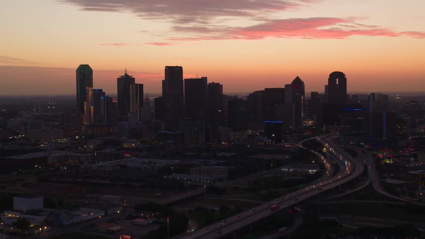Aerial view of a city skyline at dawn with a prominent highway leading into downtown