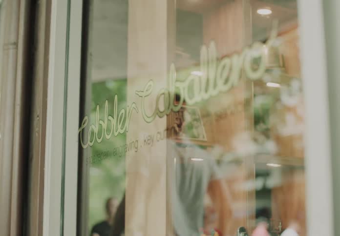 Close up of a glass door for a shop as it reflects pedestrians walking by during the day