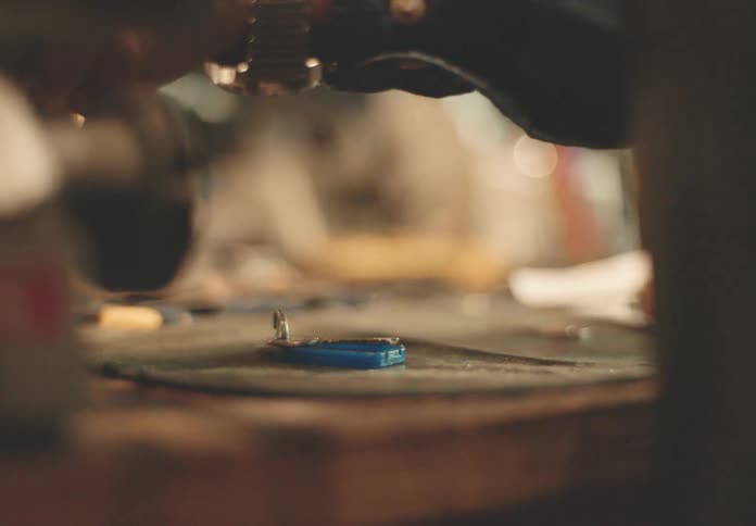 A keysmith working at a table with a key