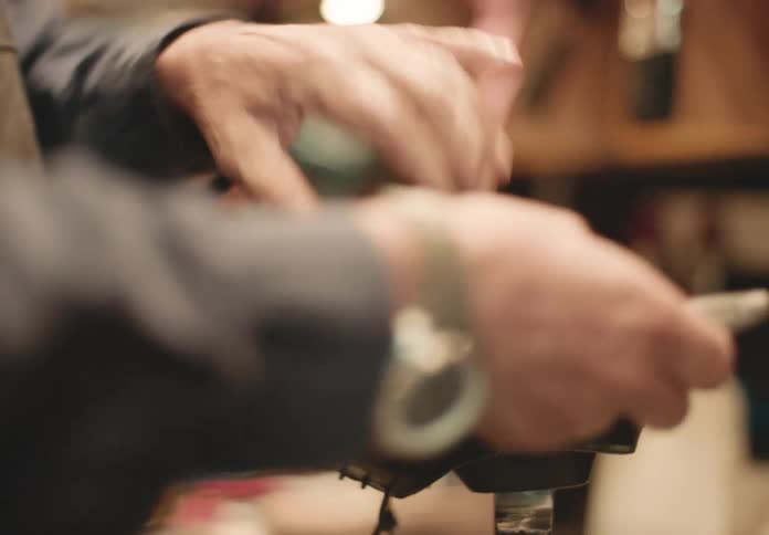 Cobbler removes a sole from a shoe while working in his workshop
