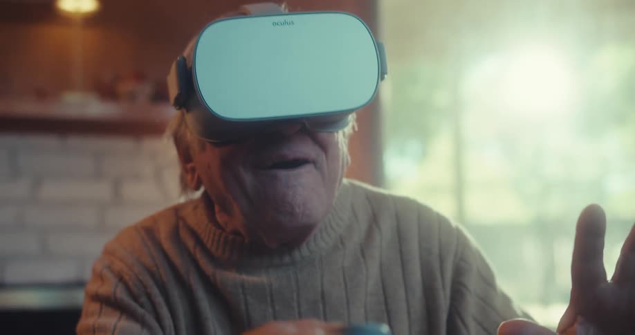 An elderly man amazed as he plays a virtual reality game with vr googles in a room