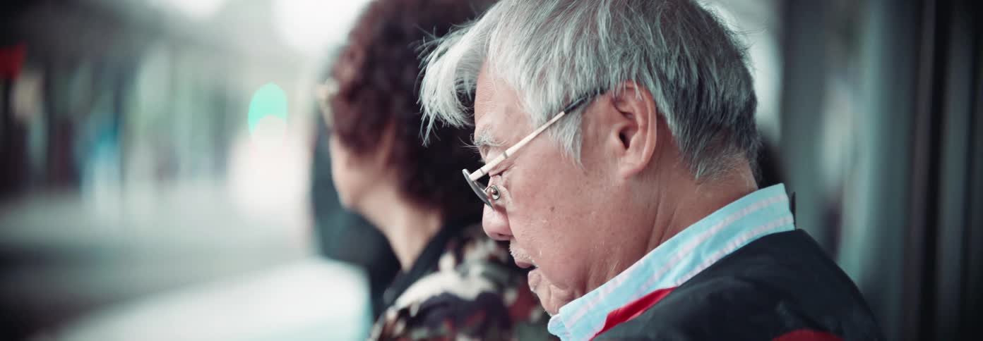 An elderly man sitting at a train station terminal