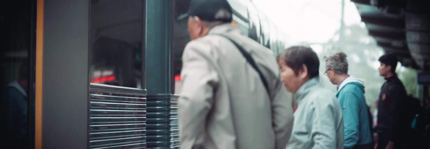 An elderly man and other people waiting for a subway