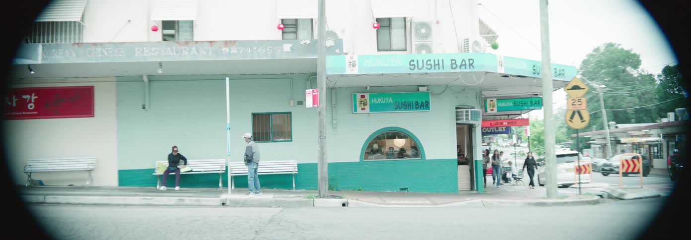 Pedestrians walk out of the sushi bar