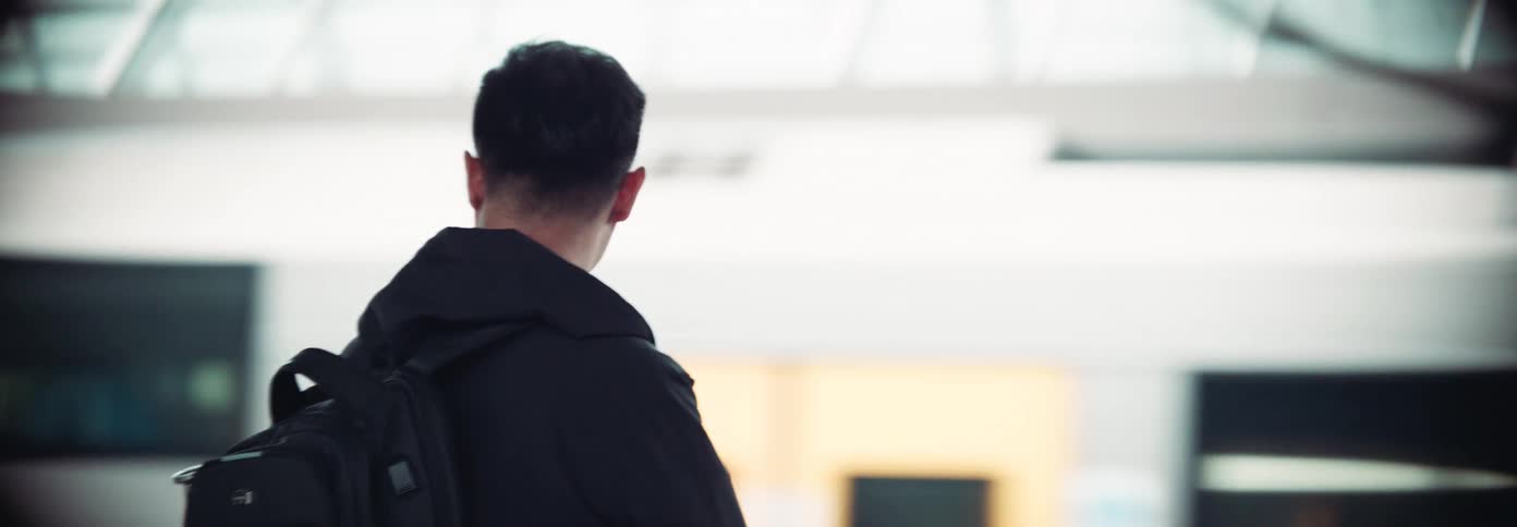 A man with a backpack stands on a train platform as a train speeds past him