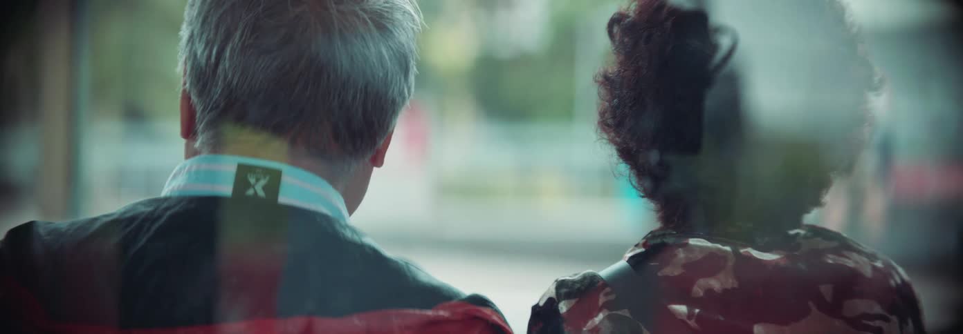 Two people sit closely together seen from behind possibly waiting or traveling