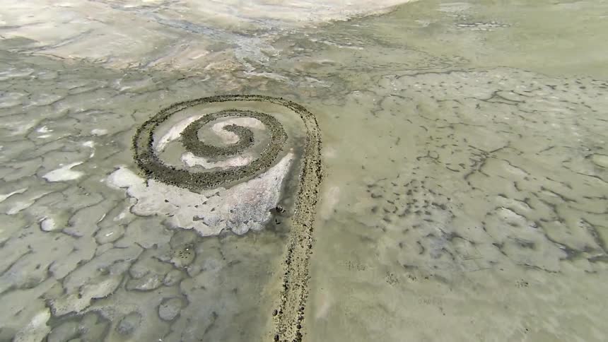 A spiral design is etched into a dirt field
