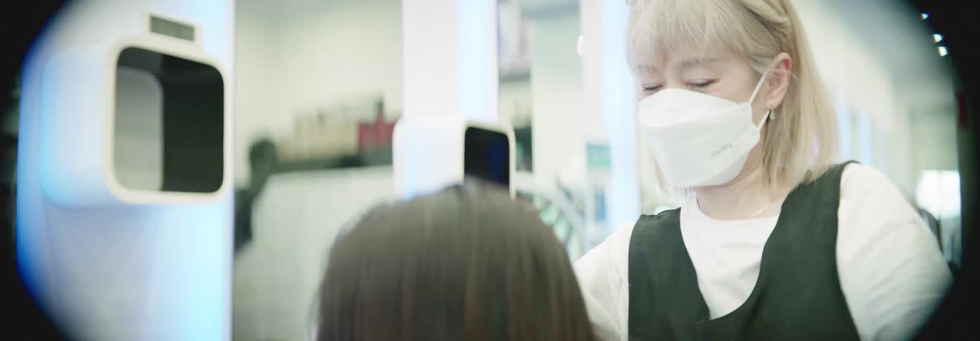 A hairdresser dries a womans hair using a hair dryer in a hair saloon