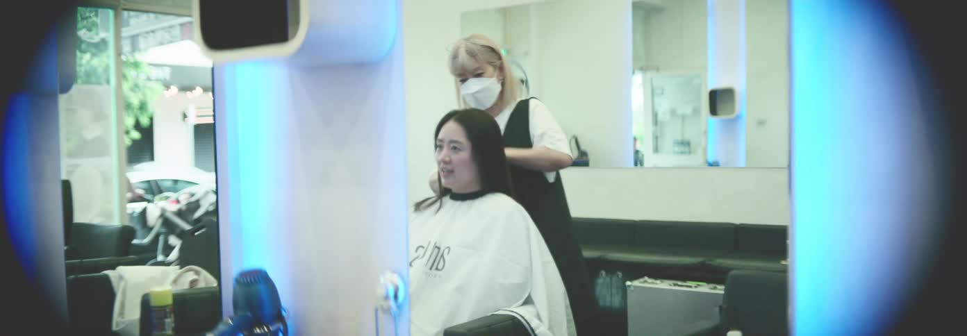Women getting a haircut at a salon with a hairstylist wearing a face mask