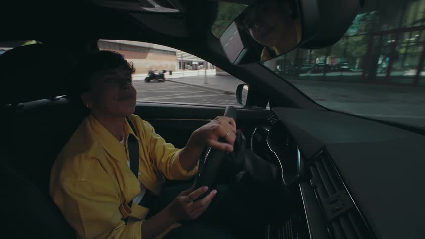Woman vibes to music as she drives along a city street during the day