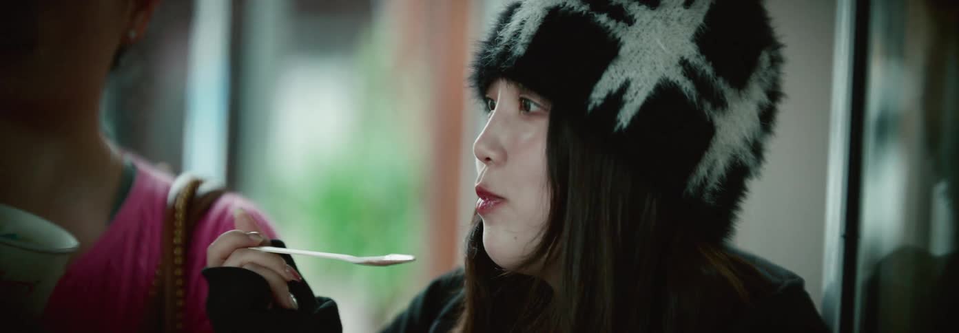 Two young women are eating frozen treats together in a casual setting