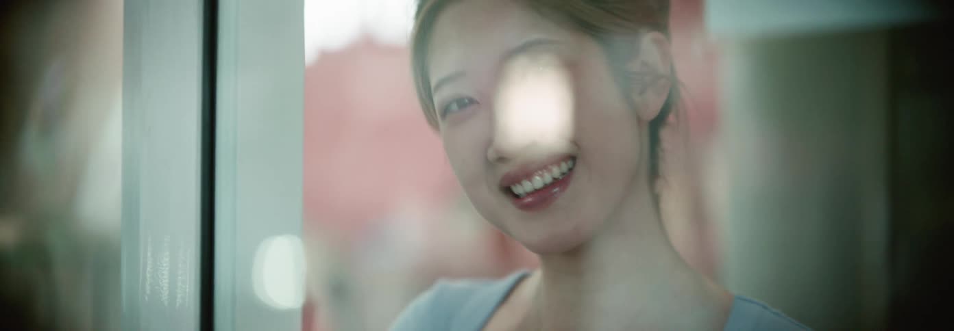 A woman waves and laughs behind the window