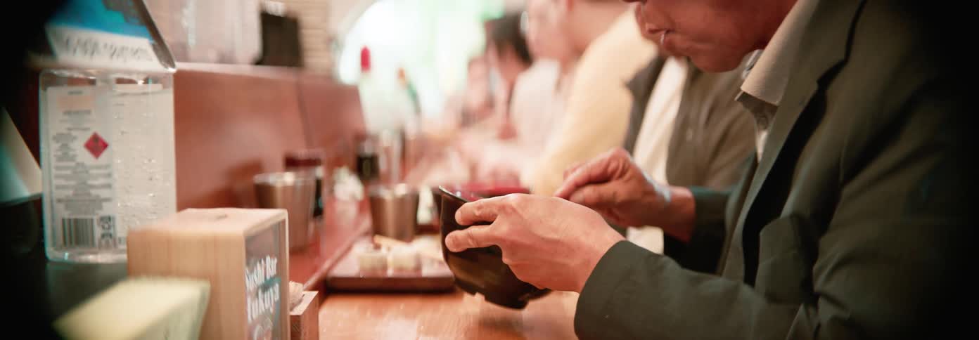 A man eating from a brown bowl in a bar at daytime