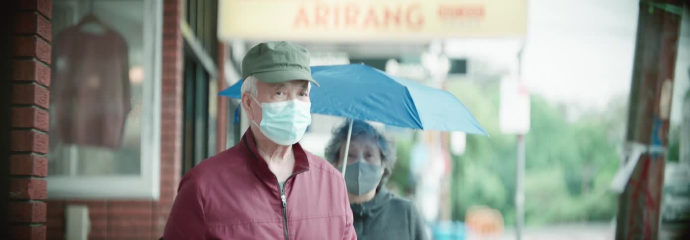 A couple walk past the shops wearing face masks