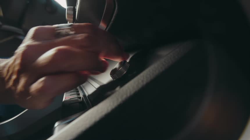 A hand adjusts a knob on a car's center console.