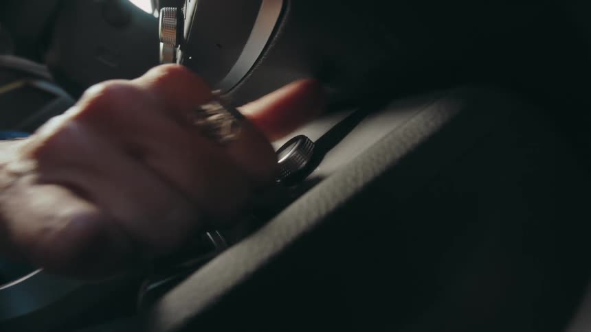 A female driver turns a knob on her car's dashboard while driving.