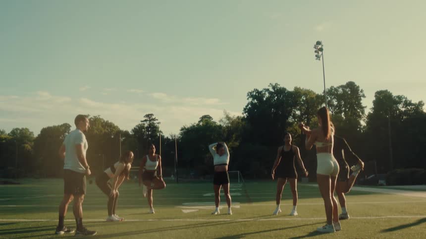 A group of people are stretching on the football field
