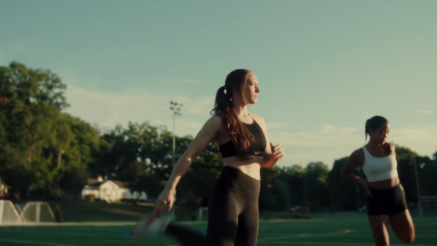 A group of people are warming up and stretching on an outdoor sports field