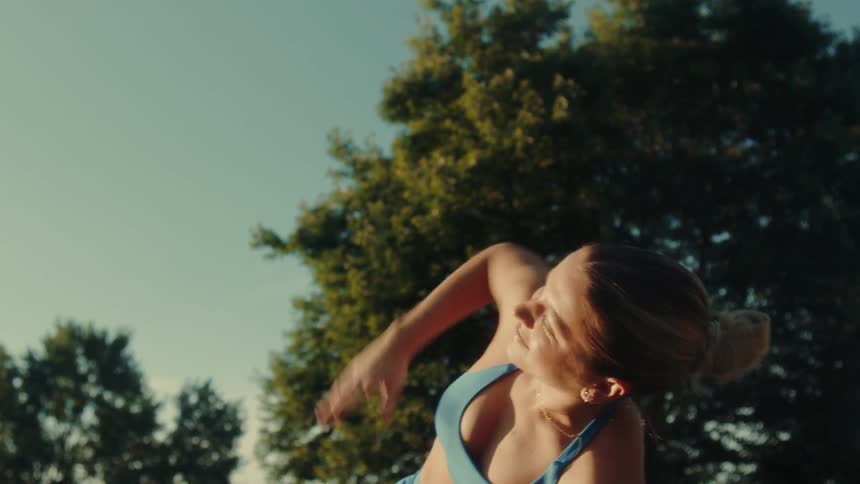 A woman in workout clothes stretches in an outdoor setting