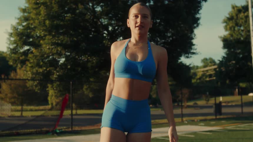 Blonde woman in blue sportswear stretching outdoors