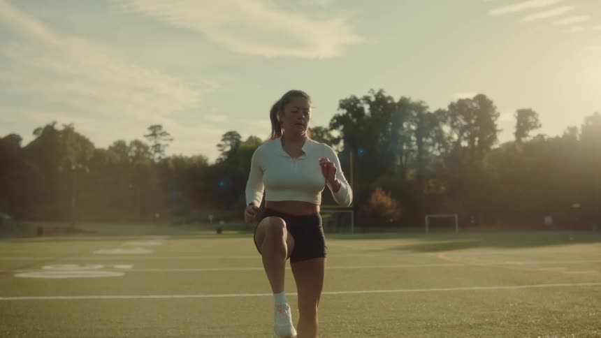 A woman exercises in the middle of a field during the day