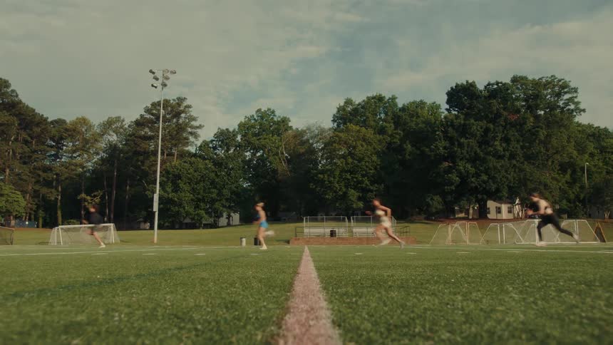 A group of people are sprinting on a sports field during a running practice or race