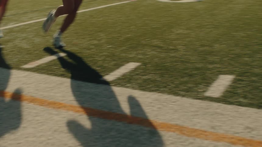 A group of people are jogging on a marked athletic field under daylight
