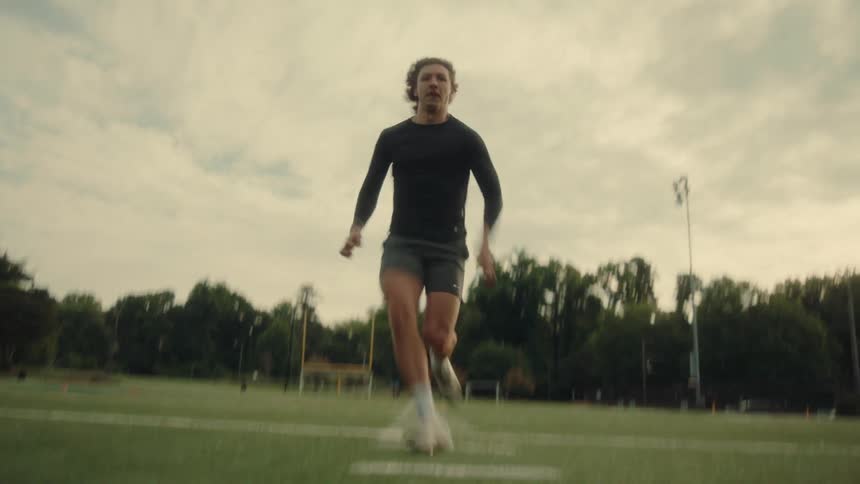 Man running at high speed across an outdoor sports grass field