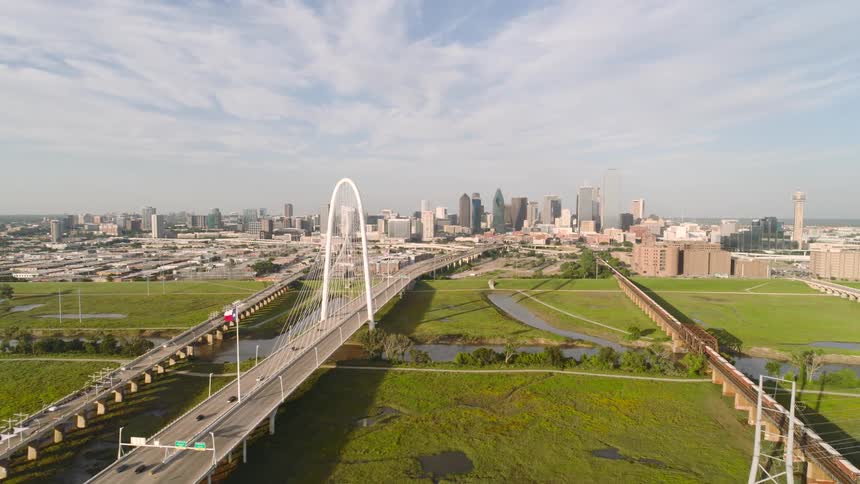 A wide aerial view of the margaret hunt hill bridge leading into downtown dallas texas