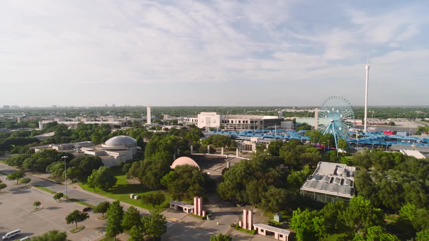 A city view filled with trees with an amusement park just around the corner at midday