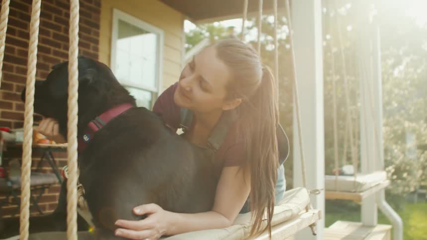 Woman petting a black dog in the backyard