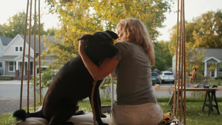 Happy woman playing and petting her dog sitting next to her