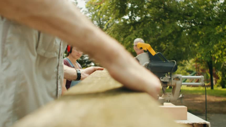 Man taking a wooden slat and placing it on a circular saw