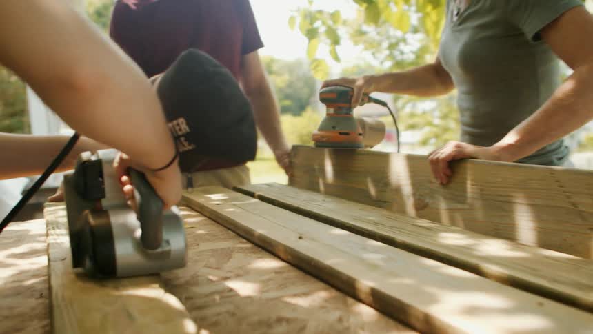 People are sanding planks of wood