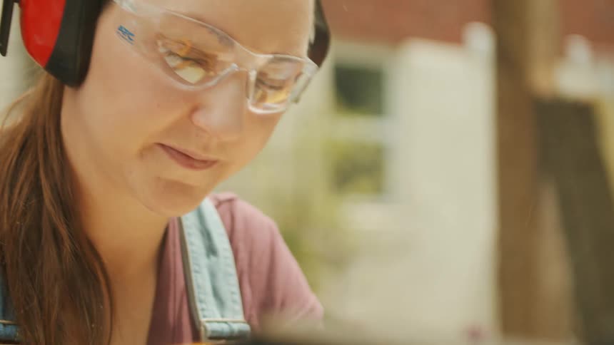 A woman operates a table saw outside