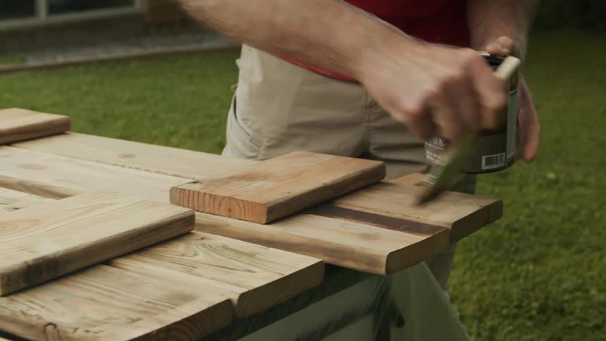 Male hands paint on wooden blocks placed on a grassy lawn