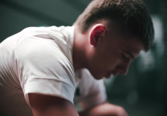 A young man is lacing his shoe getting ready for training in the gym