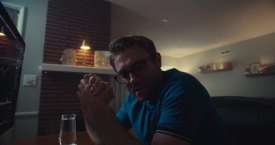 Man glances at his stock portfolio on computer and smiles subtly