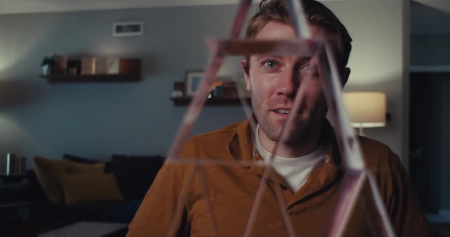A man building a house of cards in his sitting room