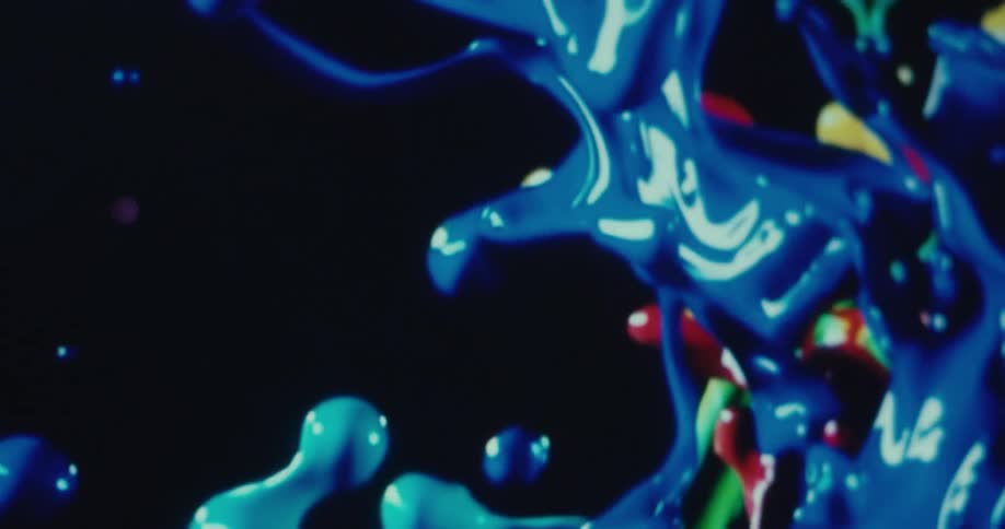 Different colors of paint thrown into the air contrast with the black background