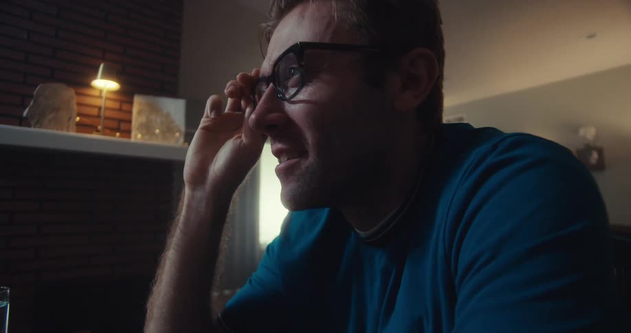 A man sits at a desk and looks at something on a computer monitor