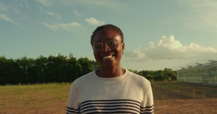 A woman standing on the farm land is smiling