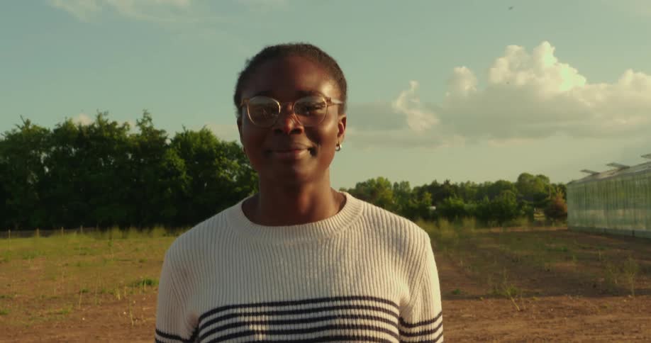 A black woman in glasses is standing in a field