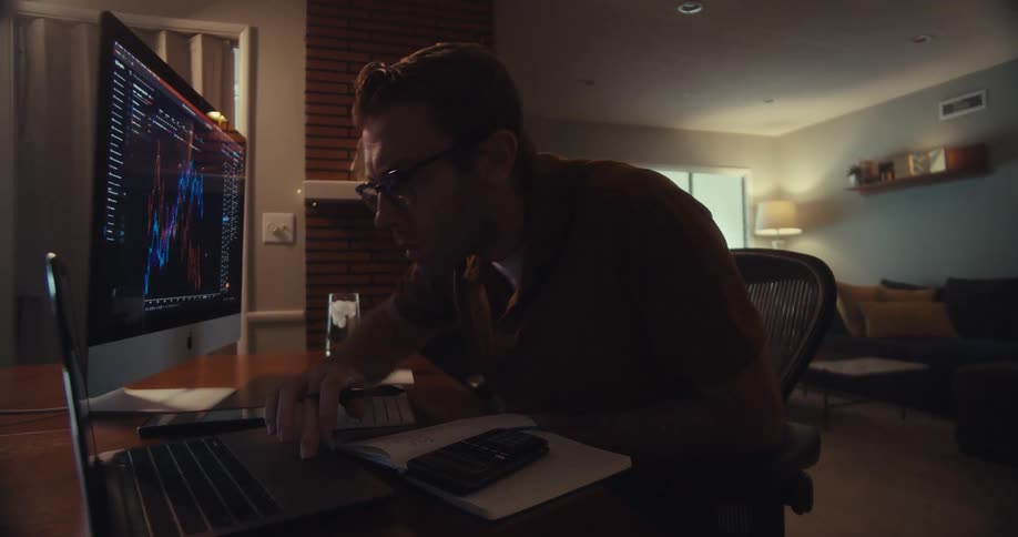 A man leans over to his laptop and to use the touch pad