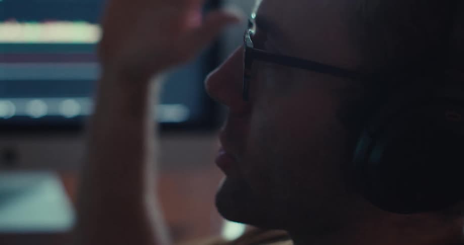 A man is talking aggressively in front of a computer while wearing headphones