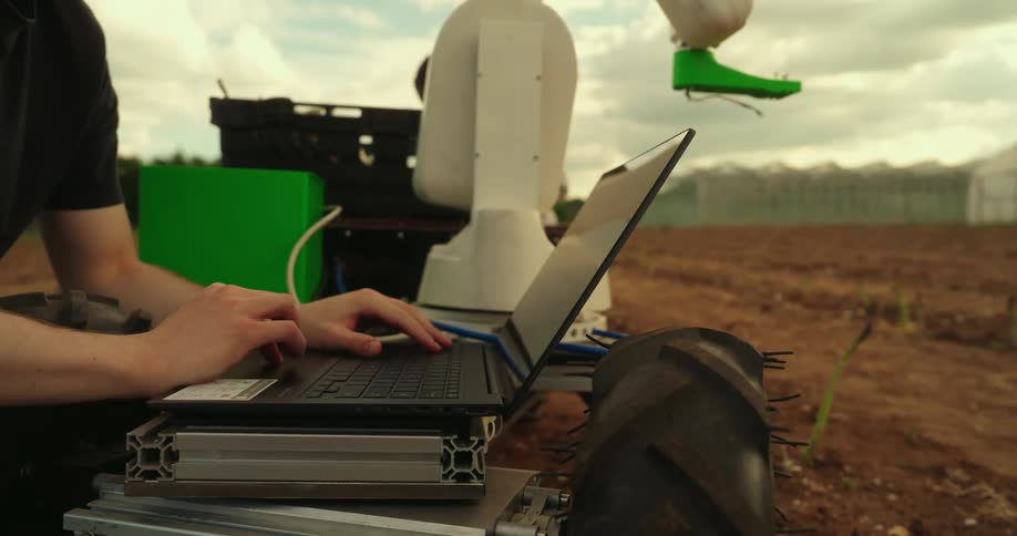 A man types on his keyboard while working on an agricultural robot