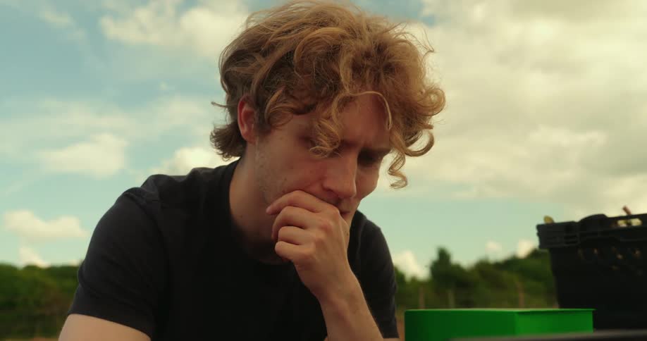 A man holds his chin while looking at a laptop on the agricultural robot